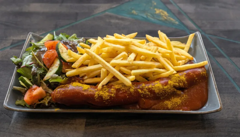 Currywurst — Große Currywurst mit Pommes und Salatbeilage bei Kaspio in Stade